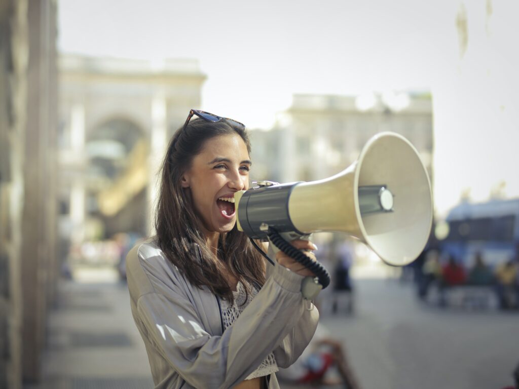 Woman standing outside holding a megaphone.